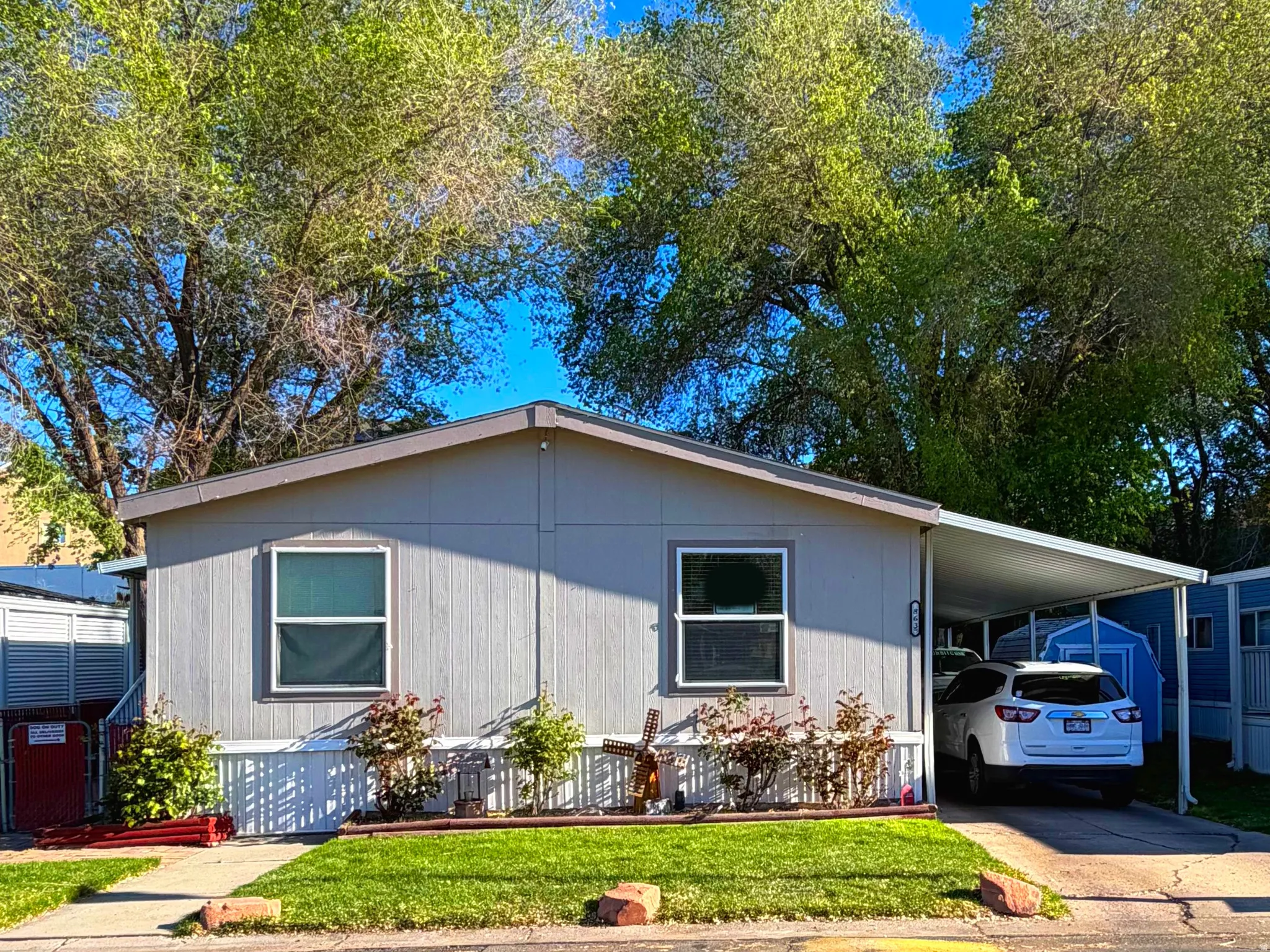 Manufactured / mobile home featuring an attached carport, a front yard, and concrete driveway