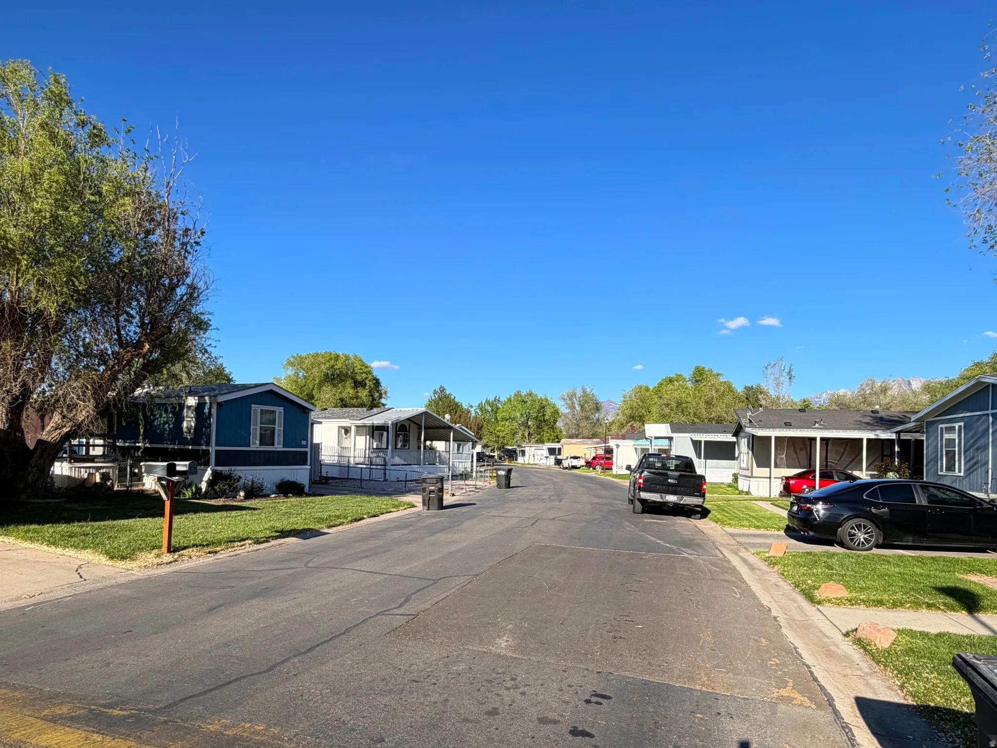 View of asphalt road featuring a residential view and curbs