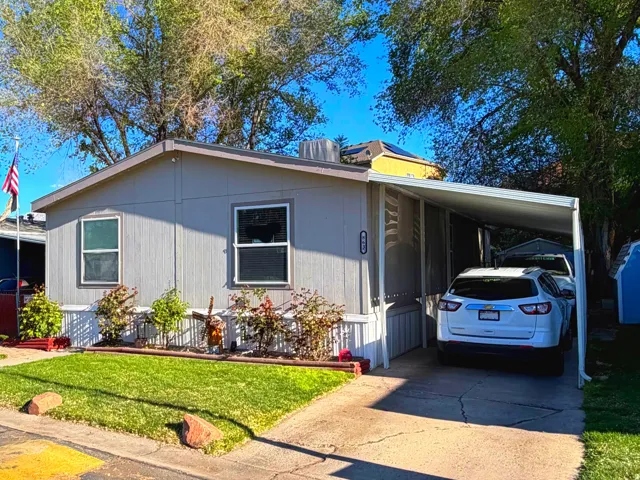 Manufactured / mobile home featuring an attached carport, a front yard, and concrete driveway
