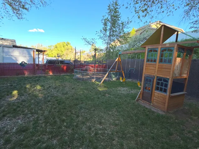 Fenced backyard featuring a playground
