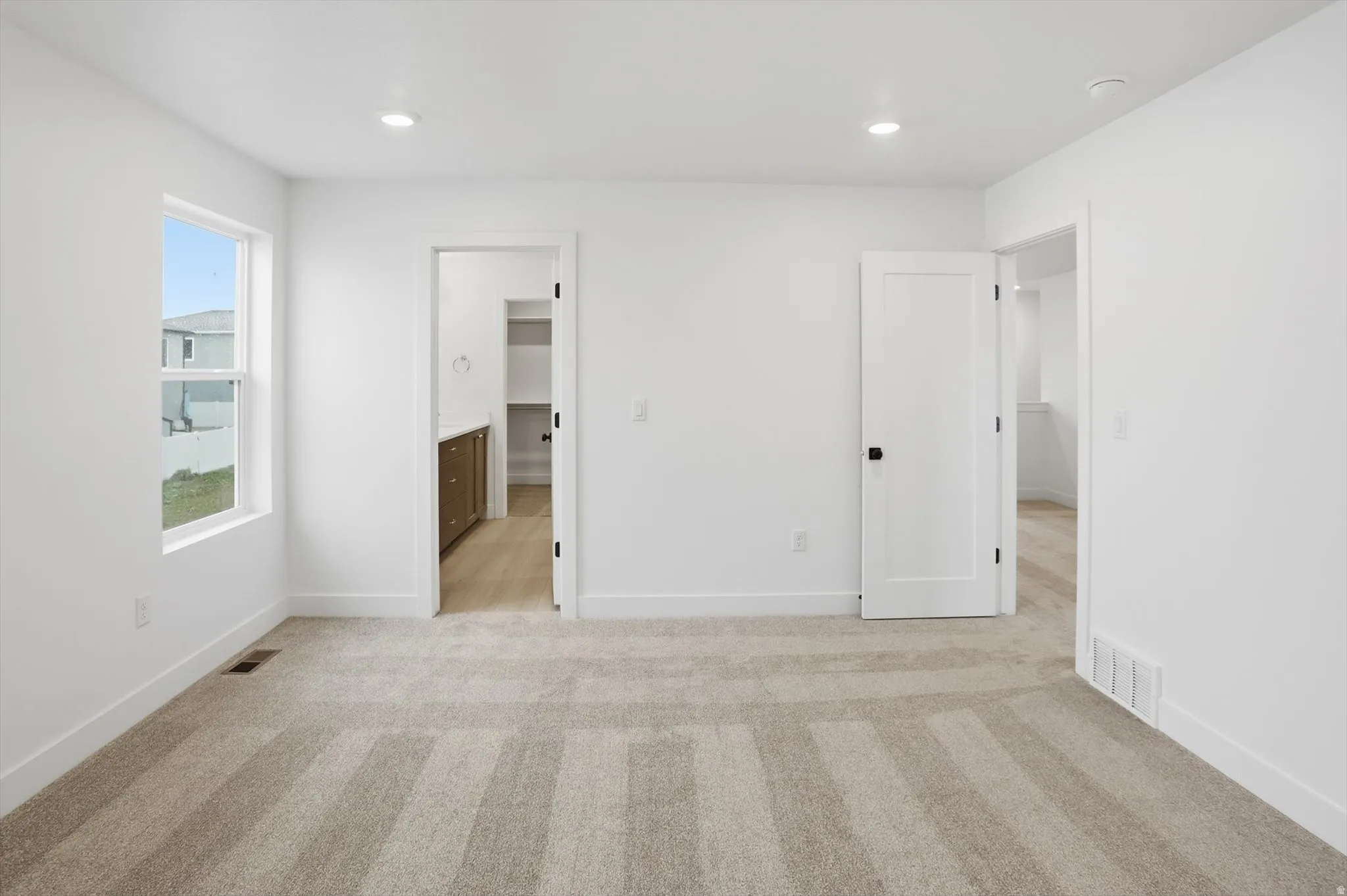 Unfurnished bedroom featuring light colored carpet, connected bathroom, and recessed lighting