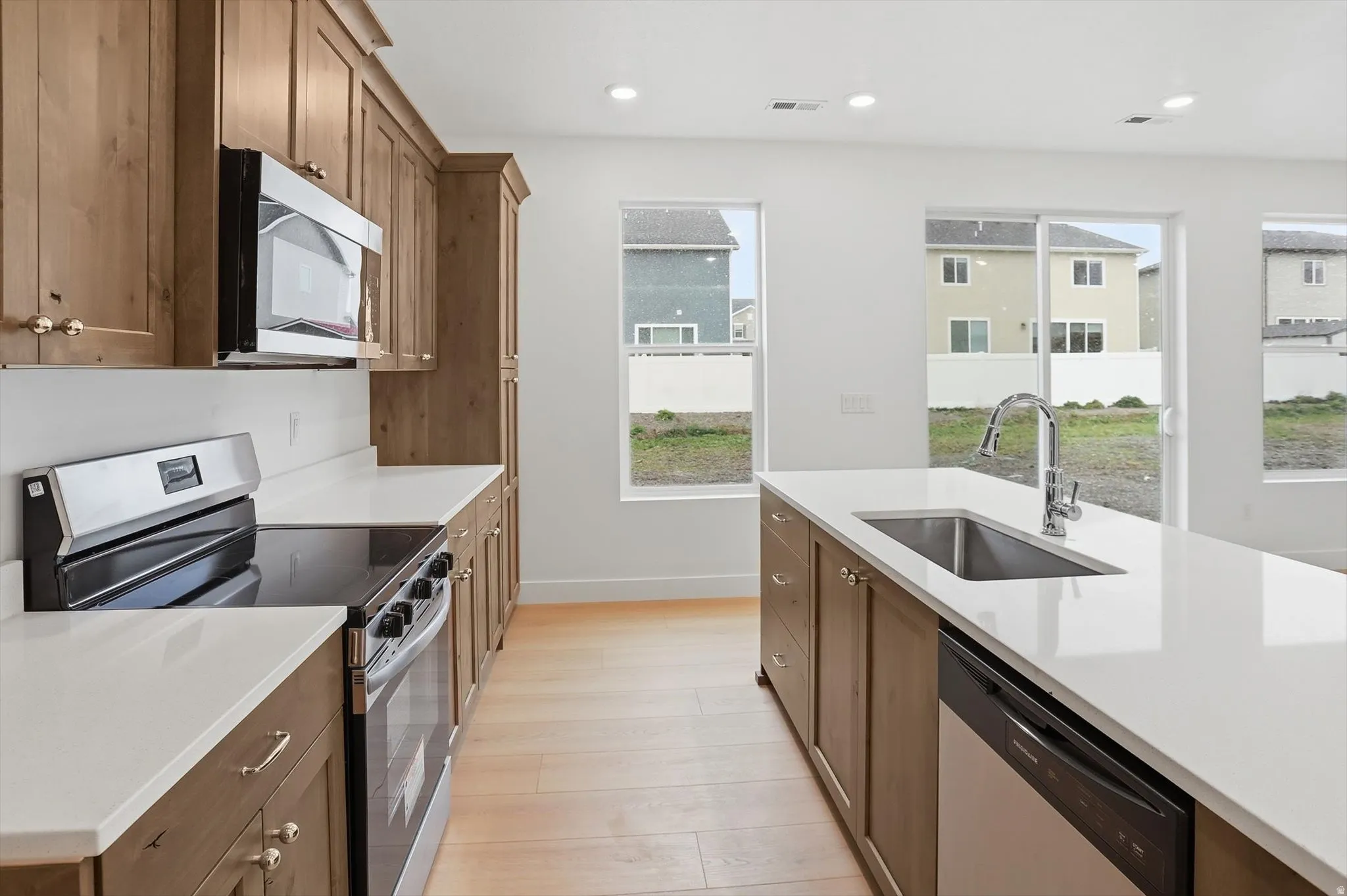 Kitchen featuring stainless steel appliances, light wood-type flooring, light stone counters, recessed lighting, and wood finish cabinetry