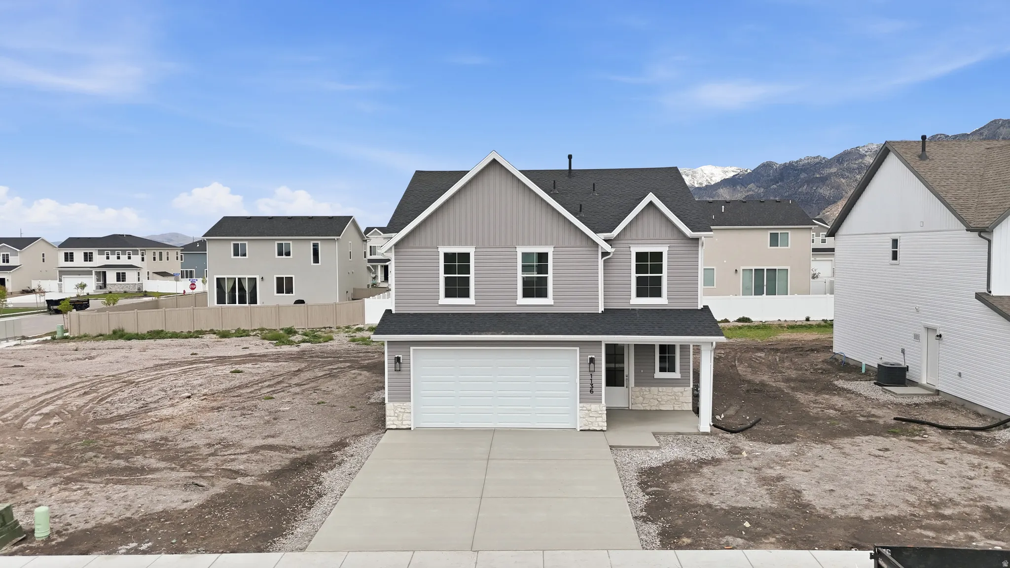 View of front of property featuring a residential view, a shingled roof, stone siding, board and batten siding, and driveway