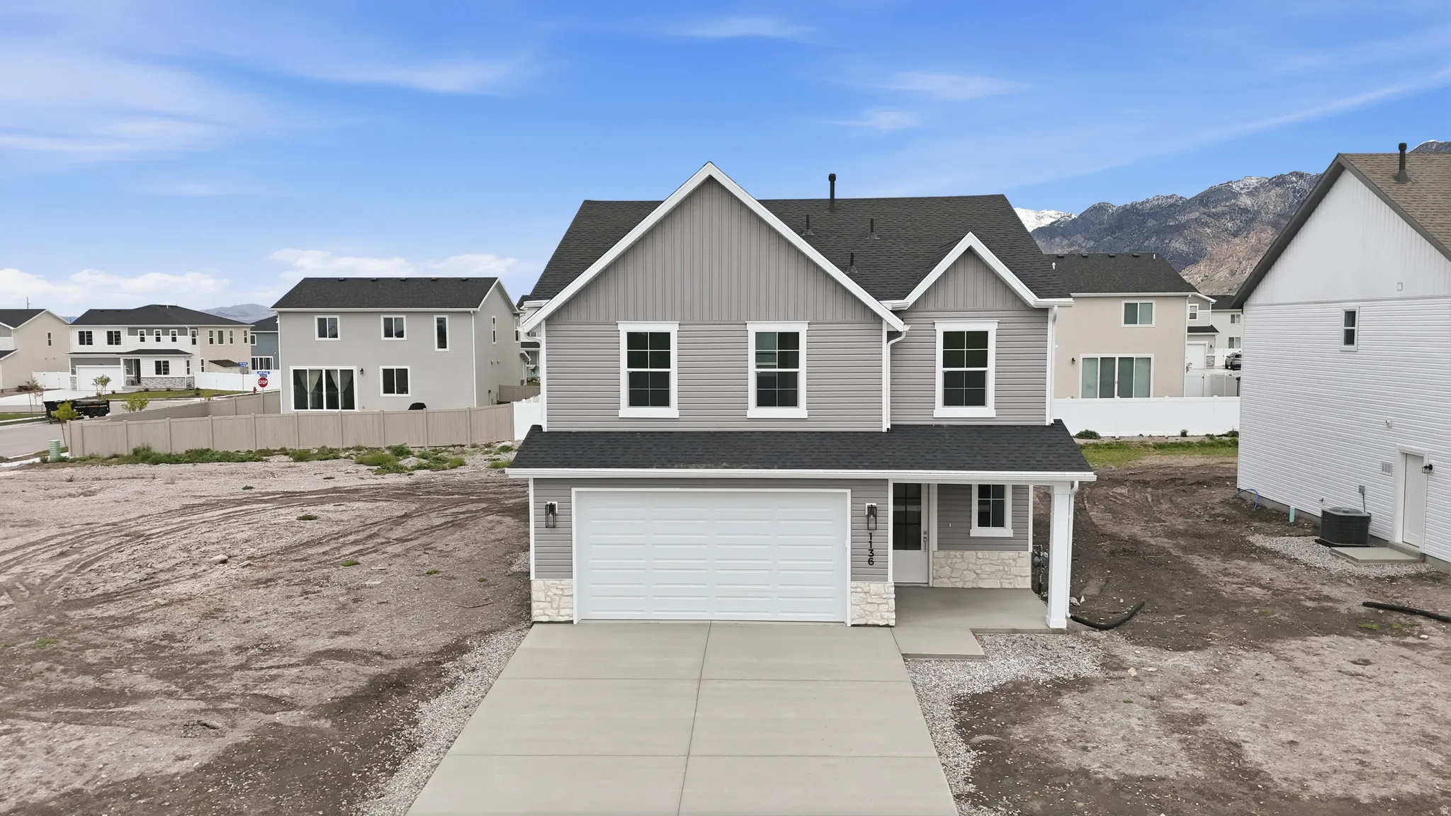 View of front of property with a residential view, a shingled roof, board and batten siding, an attached garage, and stone siding