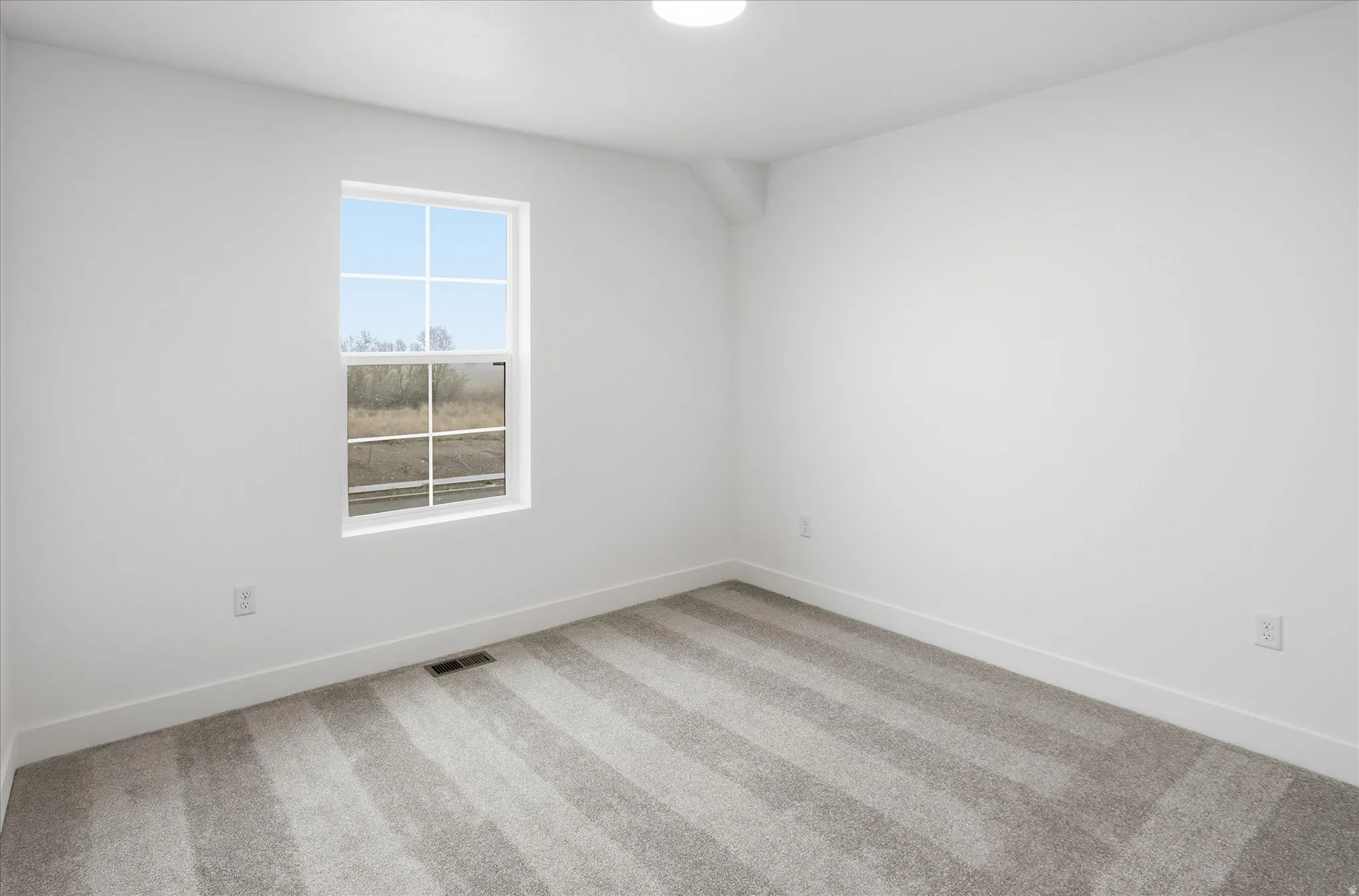 Empty room featuring baseboards and light carpet