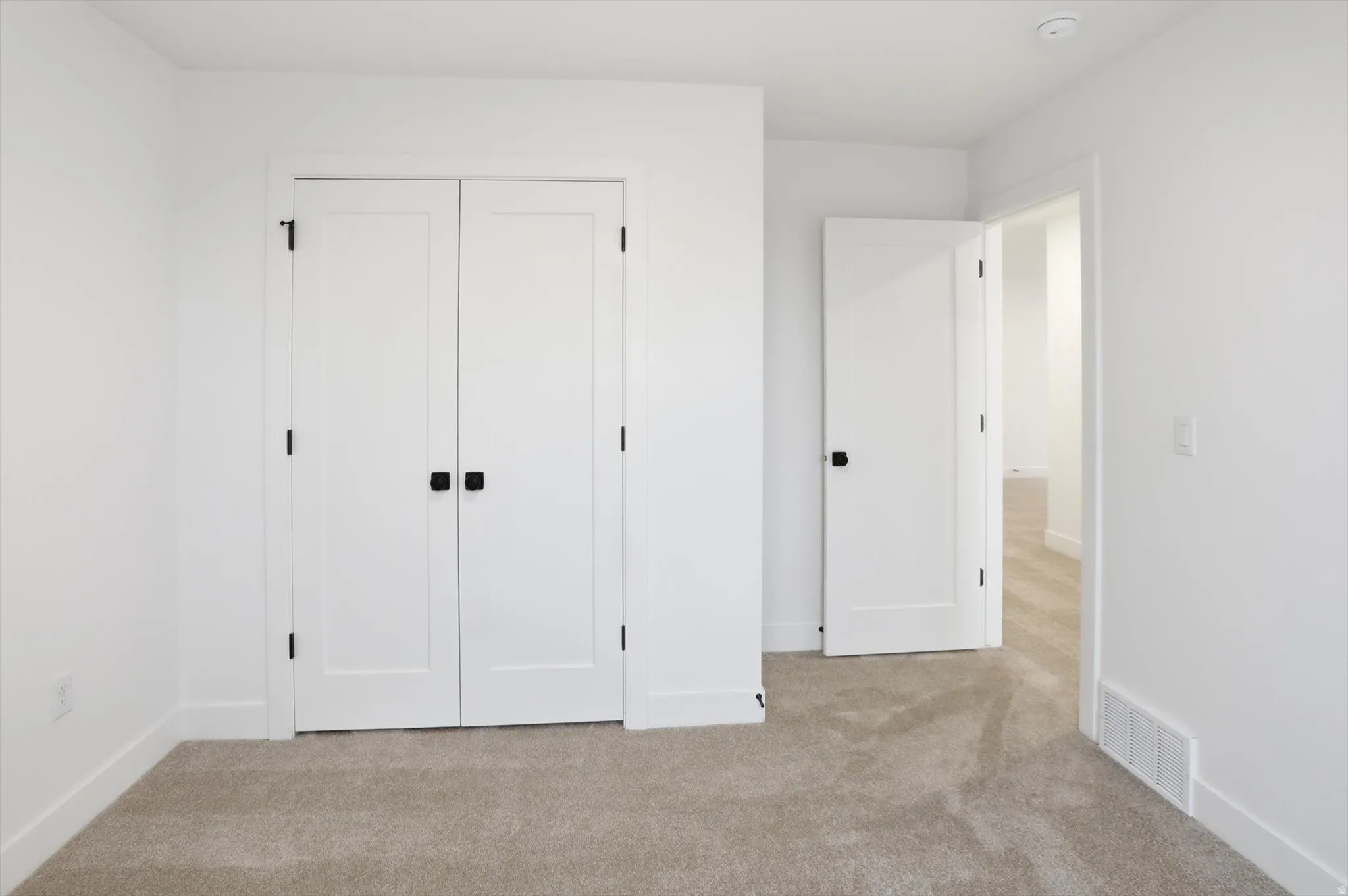 Unfurnished bedroom with light carpet and a closet
