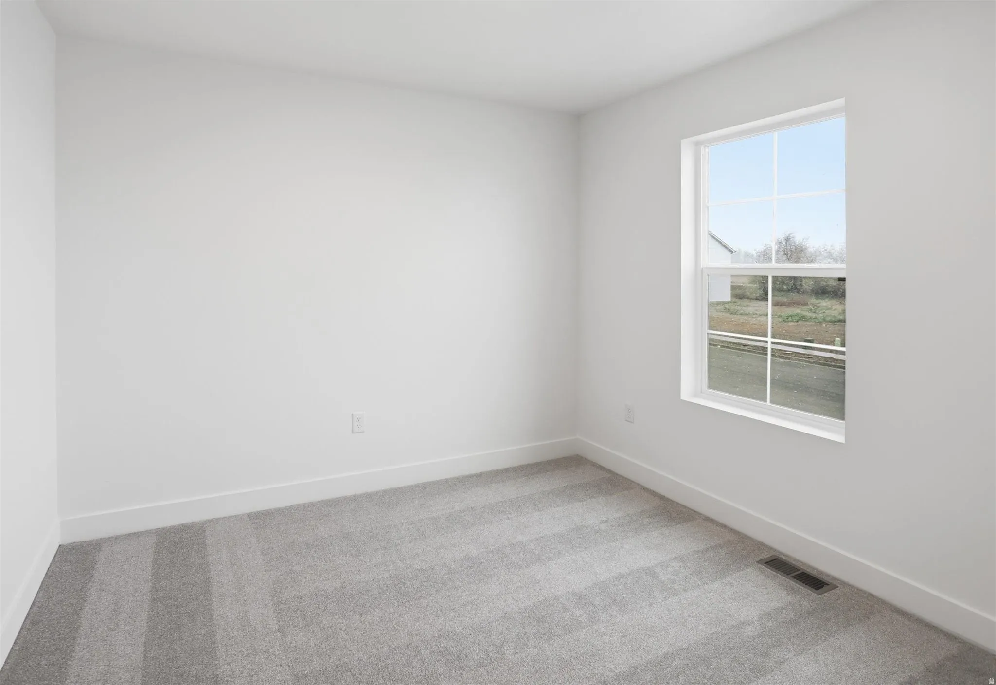 Spare room featuring light carpet and baseboards