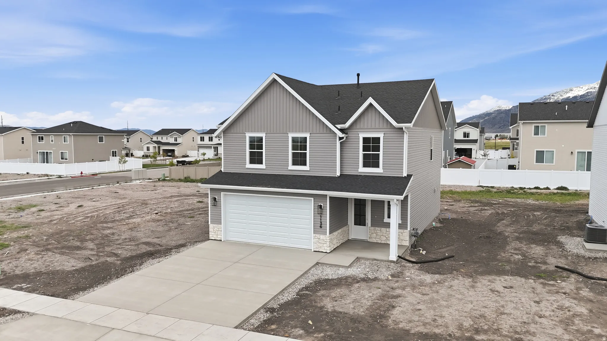 View of front of house featuring a residential view, stone siding, board and batten siding, concrete driveway, and a garage