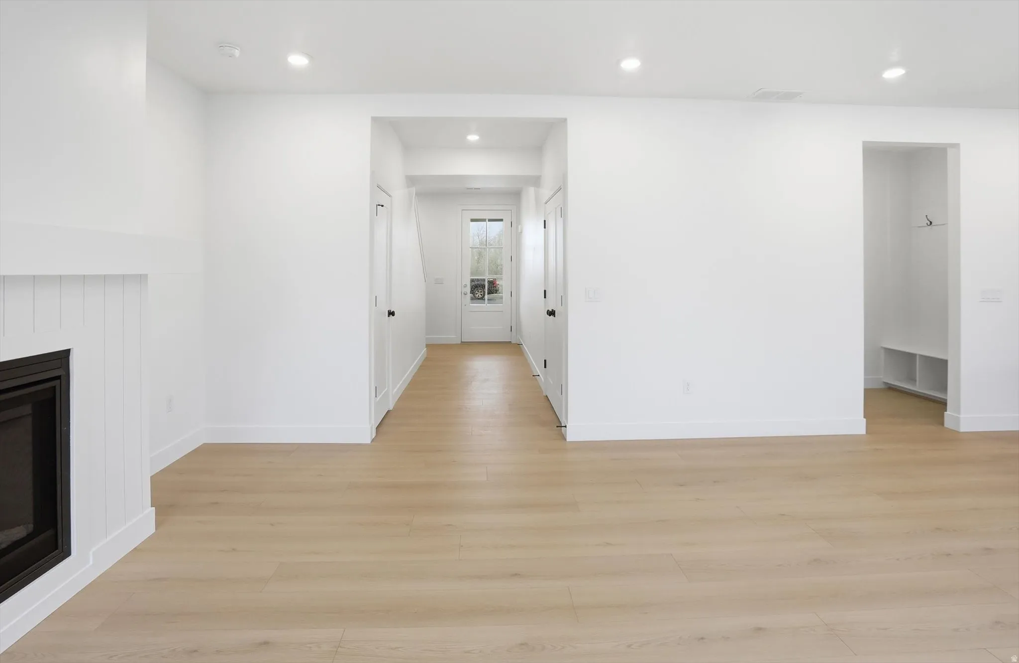Unfurnished living room with light wood-style floors, a glass covered fireplace, and recessed lighting