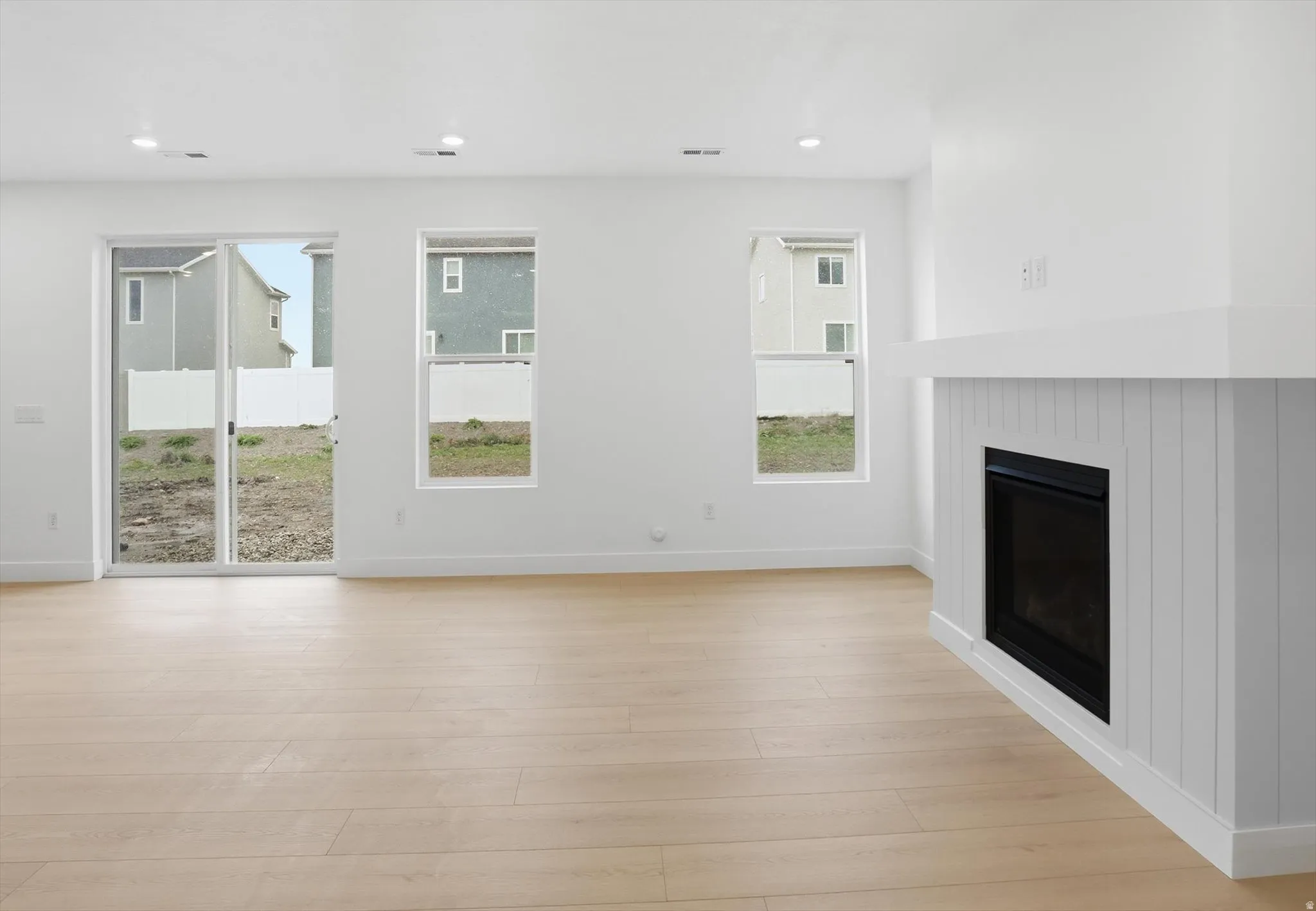 Unfurnished living room with a glass covered fireplace, light wood-style flooring, and recessed lighting