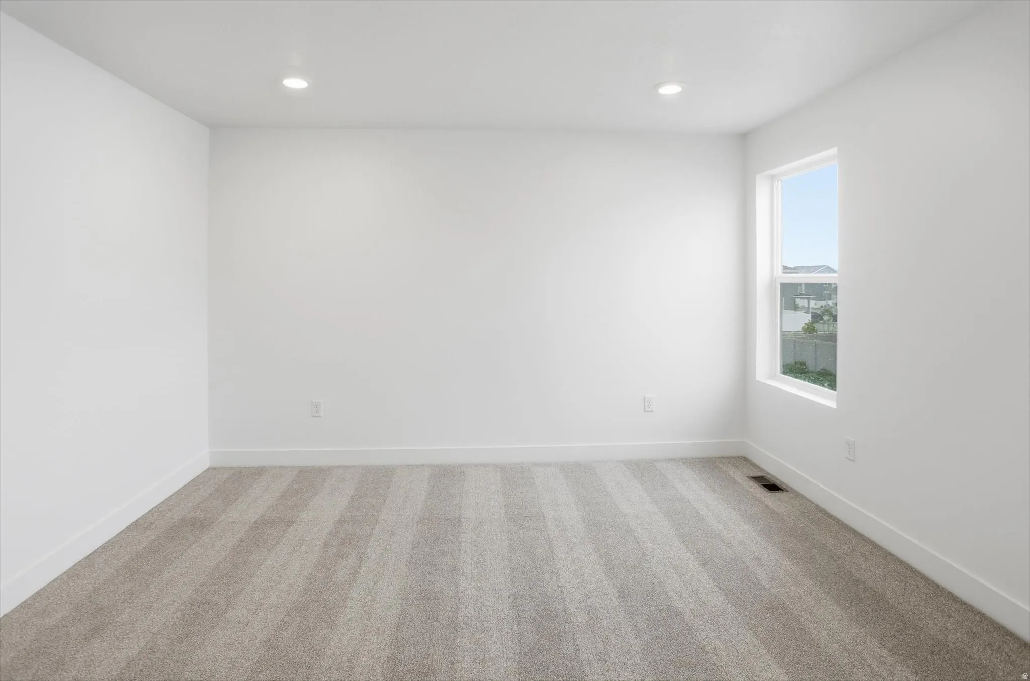 Unfurnished room with light colored carpet and recessed lighting