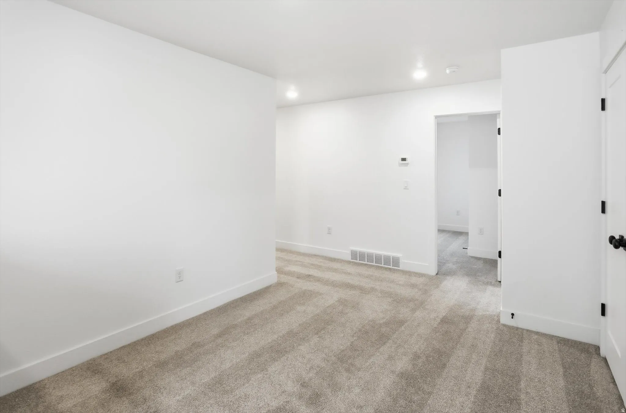 Spare room featuring light colored carpet and recessed lighting