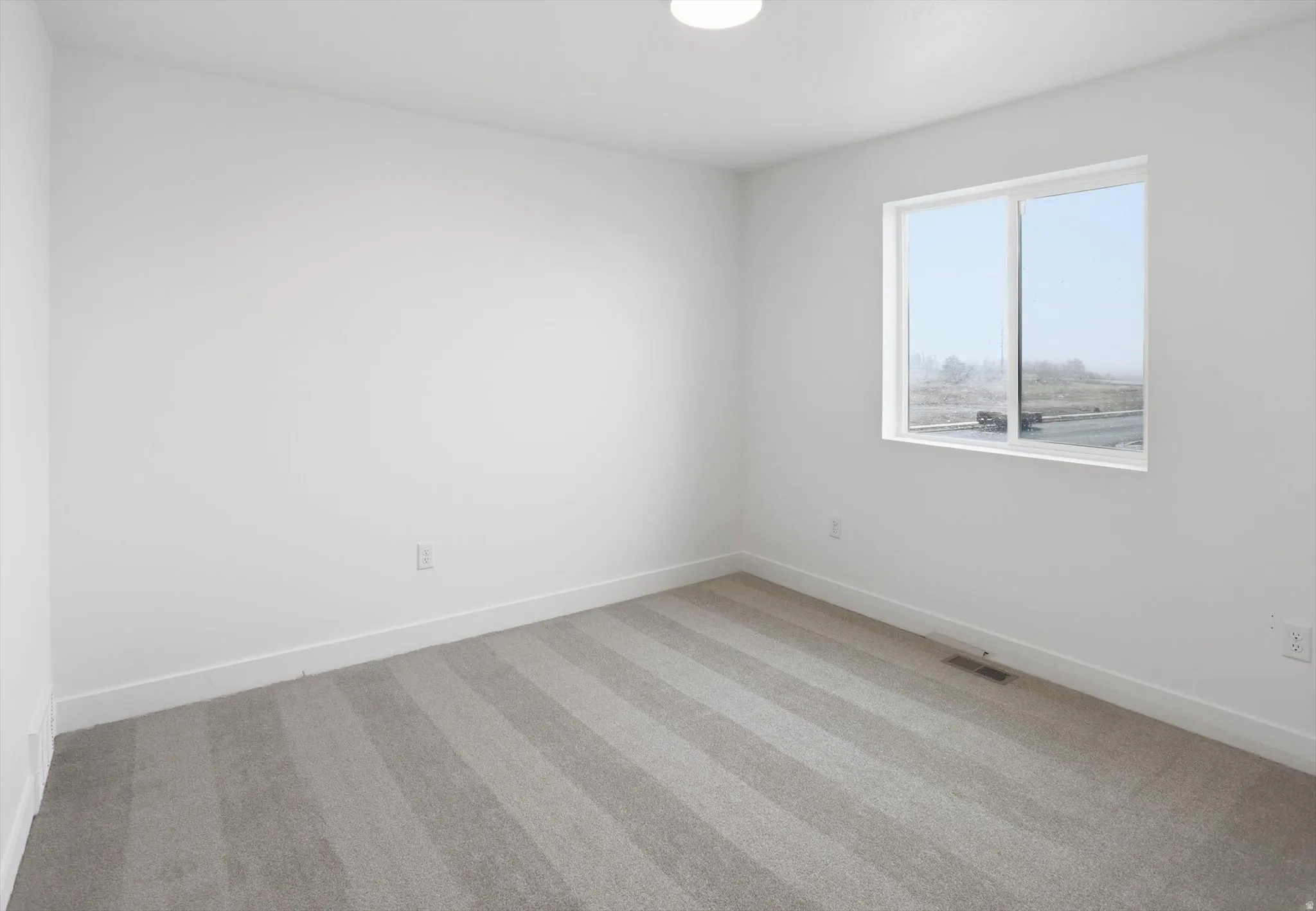 Spare room with light carpet and baseboards