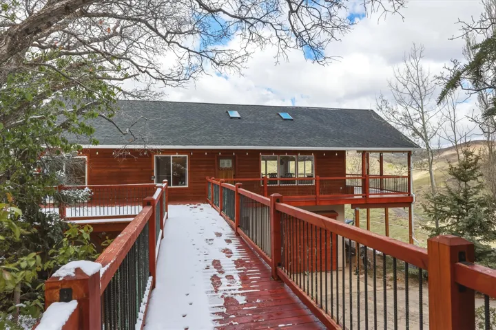 Snow covered back of property with a shingled roof