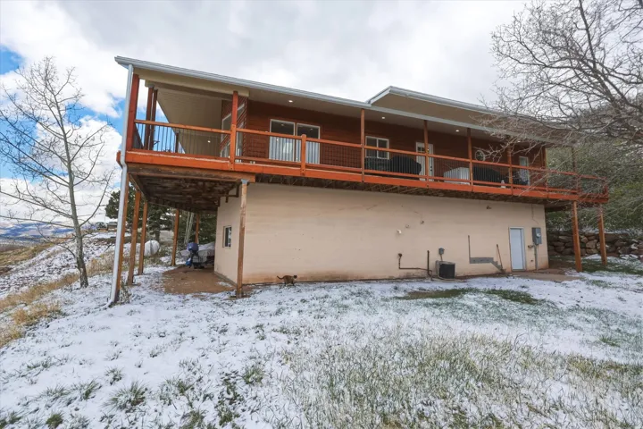 Snow covered back of property with a deck