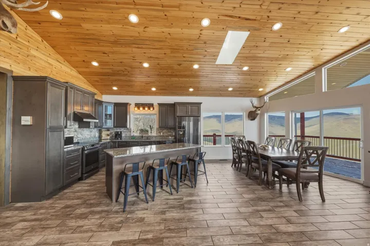 Kitchen with a vaulted wood ceiling, dark wood finish cabinets, dark stone countertops, a mountain view, and a large island