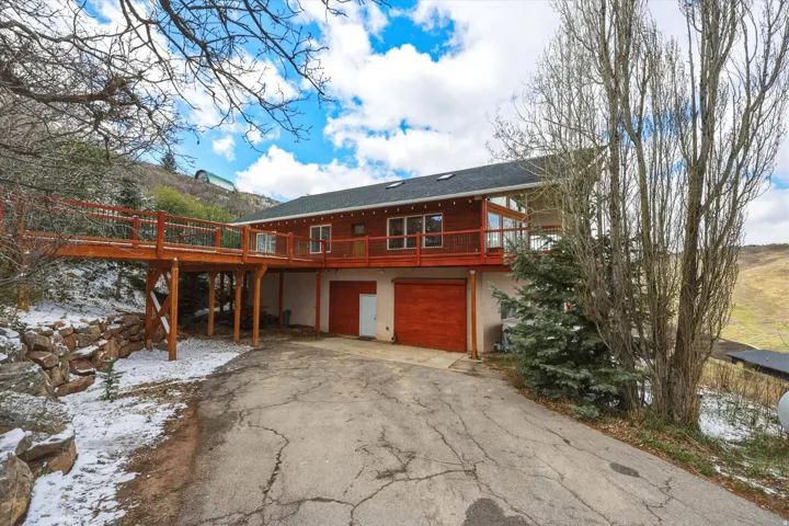 View of front of property featuring asphalt driveway, an attached garage, stucco siding, and a deck