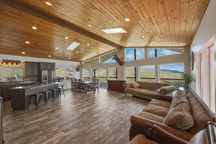 Living area featuring a high wooden beamed ceiling, a skylight, a mountain view, dark wood-type flooring, and recessed lighting