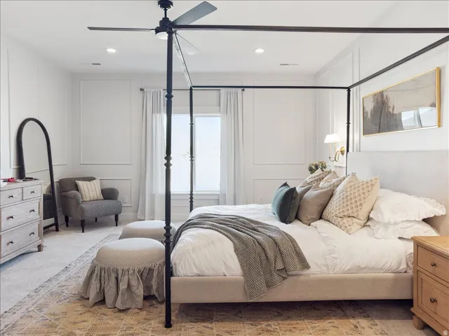 Carpeted bedroom featuring a decorative wall, ceiling fan, and recessed lighting