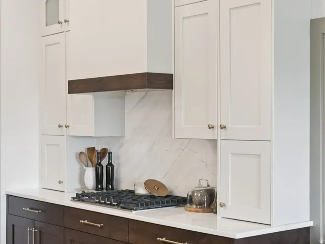 Two tone kitchen featuring dual tone cabinets, glass fronted cabinets, tasteful backsplash, and stainless steel gas stovetop