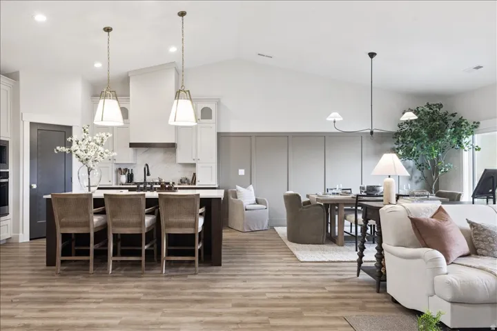 Kitchen with open floor plan, a breakfast bar area, a center island with sink, white cabinets, and light wood finished floors