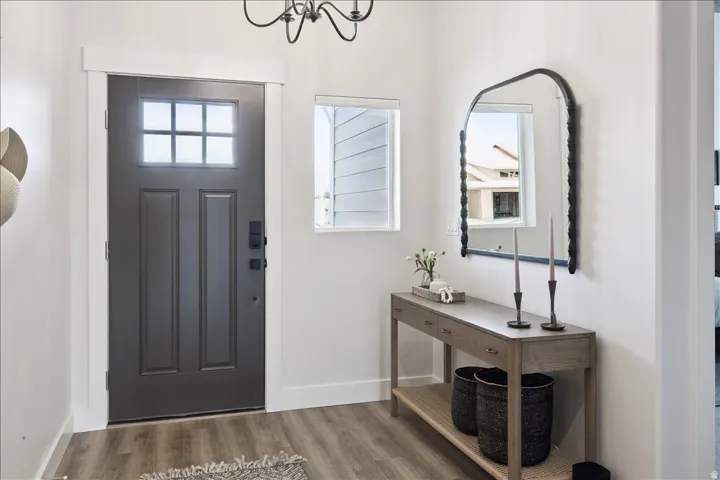Foyer entrance with plenty of natural light, wood finished floors, and a chandelier