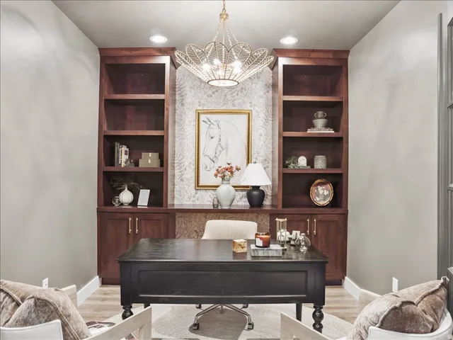 Home office featuring built in shelves, suspended lighting, and light wood-type flooring
