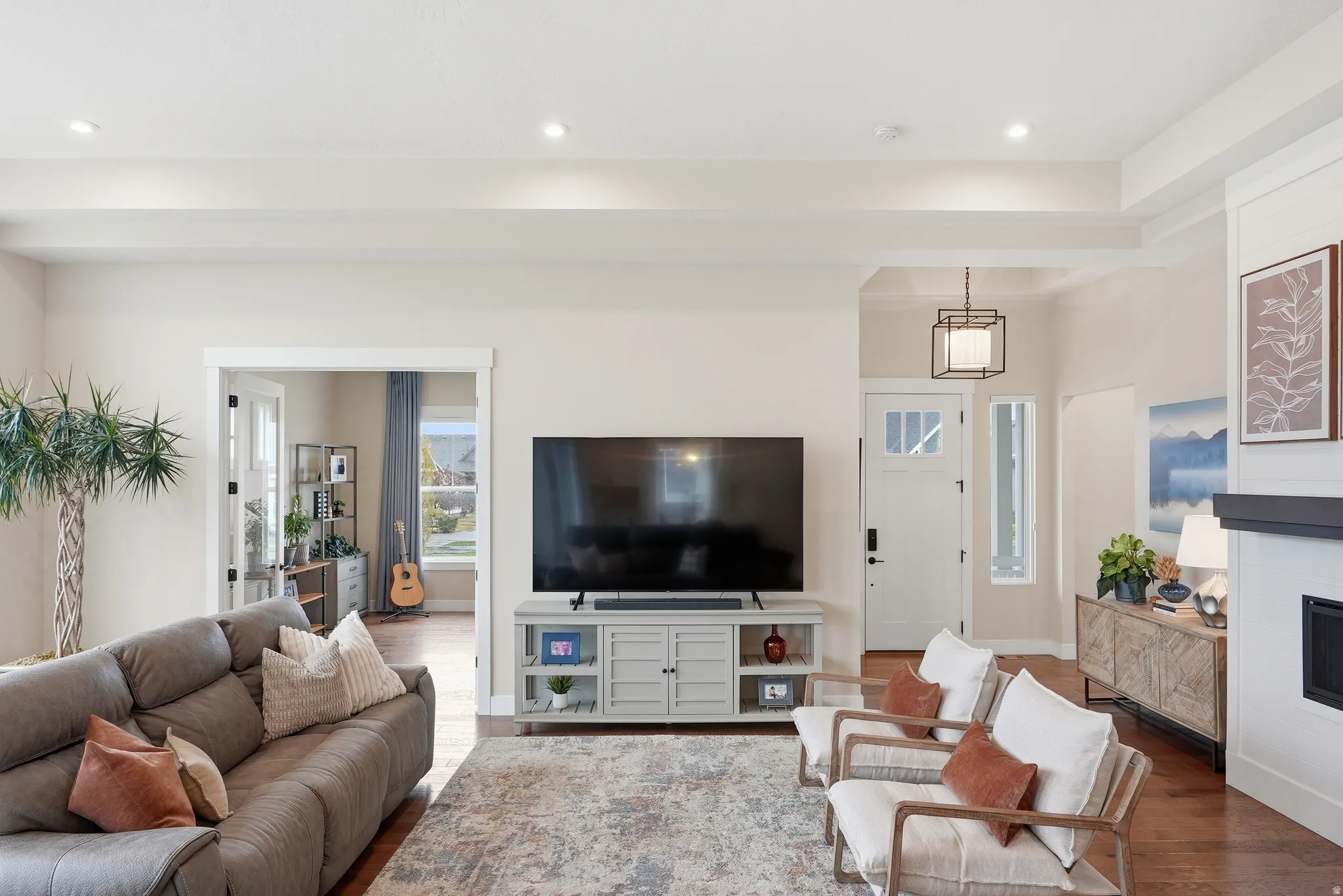 Living room with wood finished floors, a glass covered fireplace, and recessed lighting