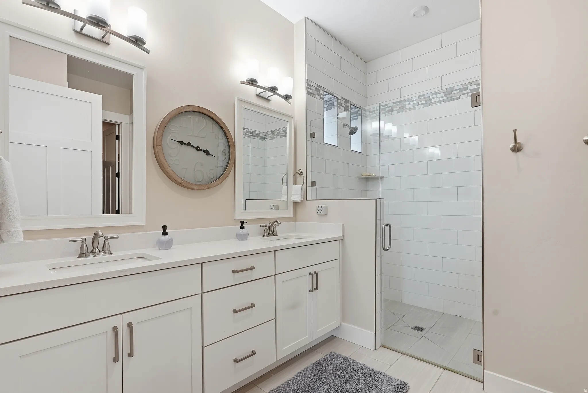 Full bath with double vanity, a shower stall, and light tile patterned floors