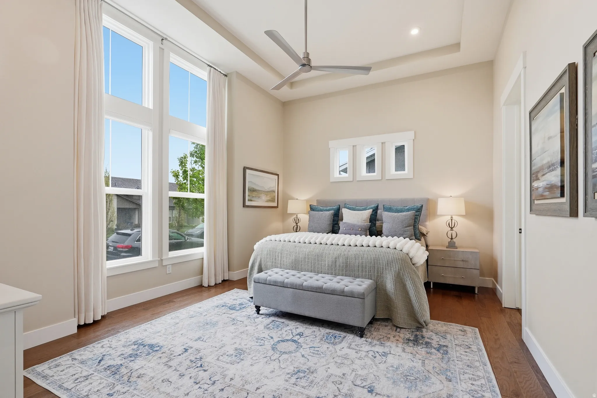 Bedroom with a raised ceiling, ceiling fan, and wood finished floors