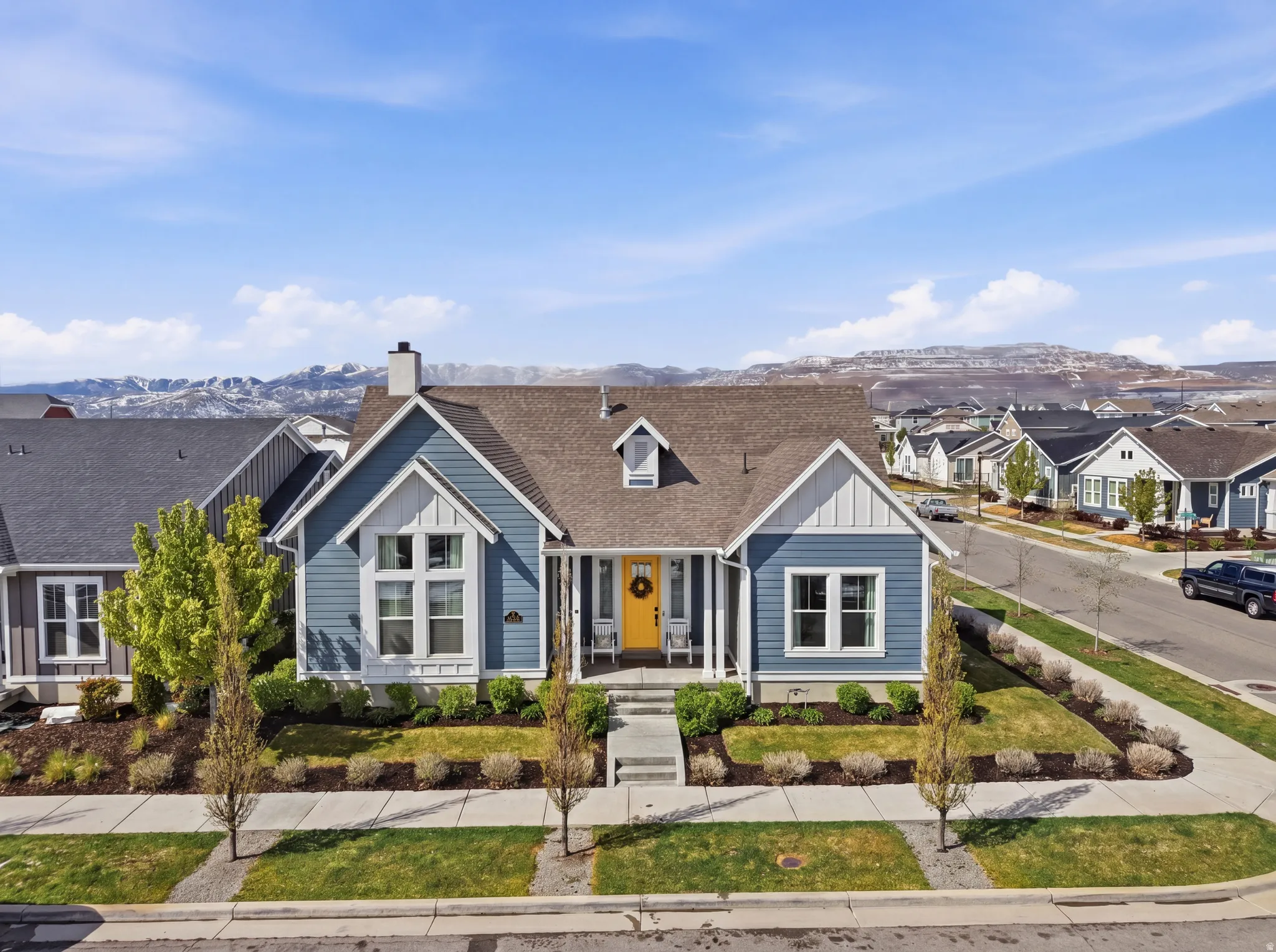 View of front of house with a mountain view, a shingled roof, a chimney, board and batten siding, and a residential view