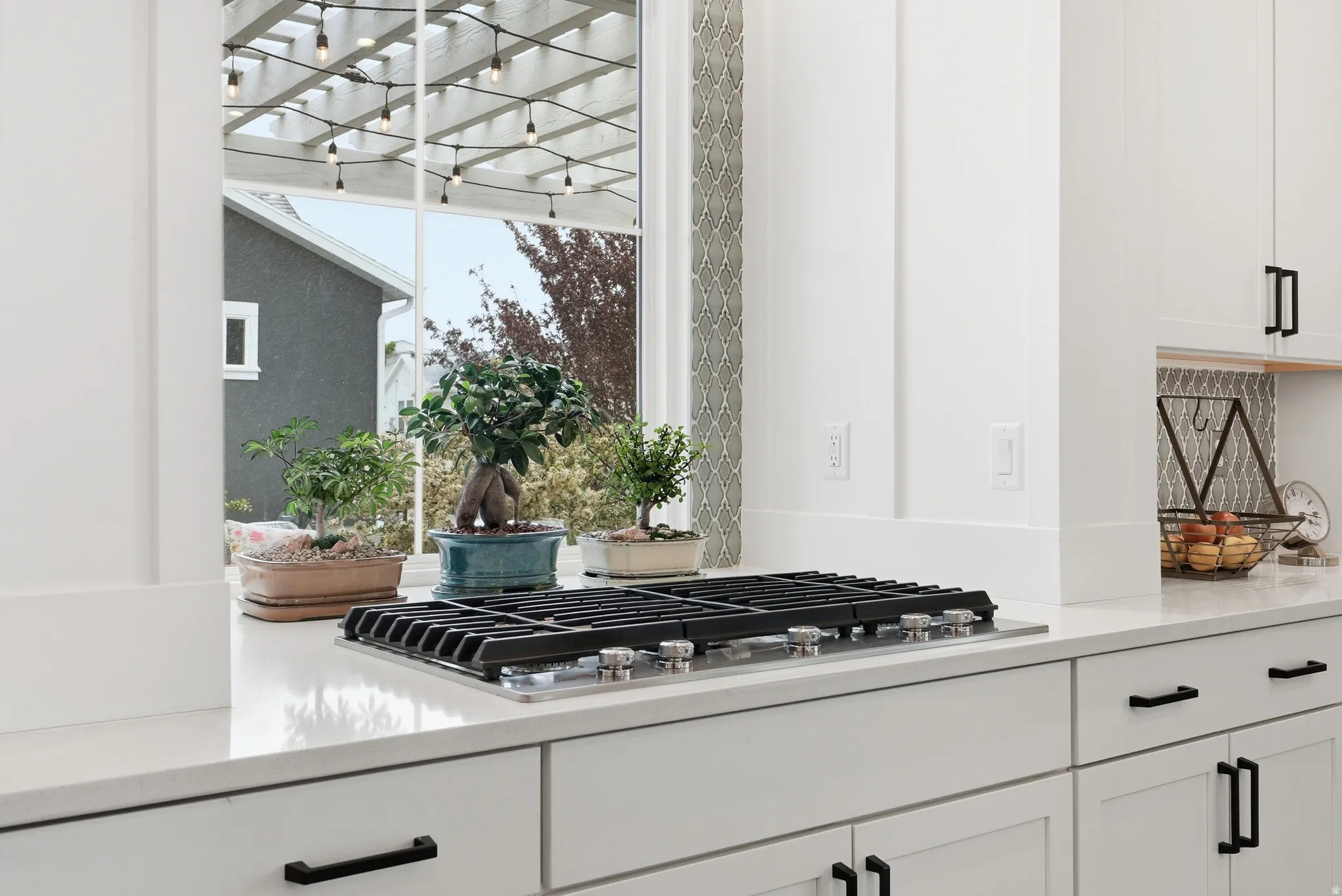 Kitchen view of white cabinets, stainless steel gas stovetop, and light stone countertops