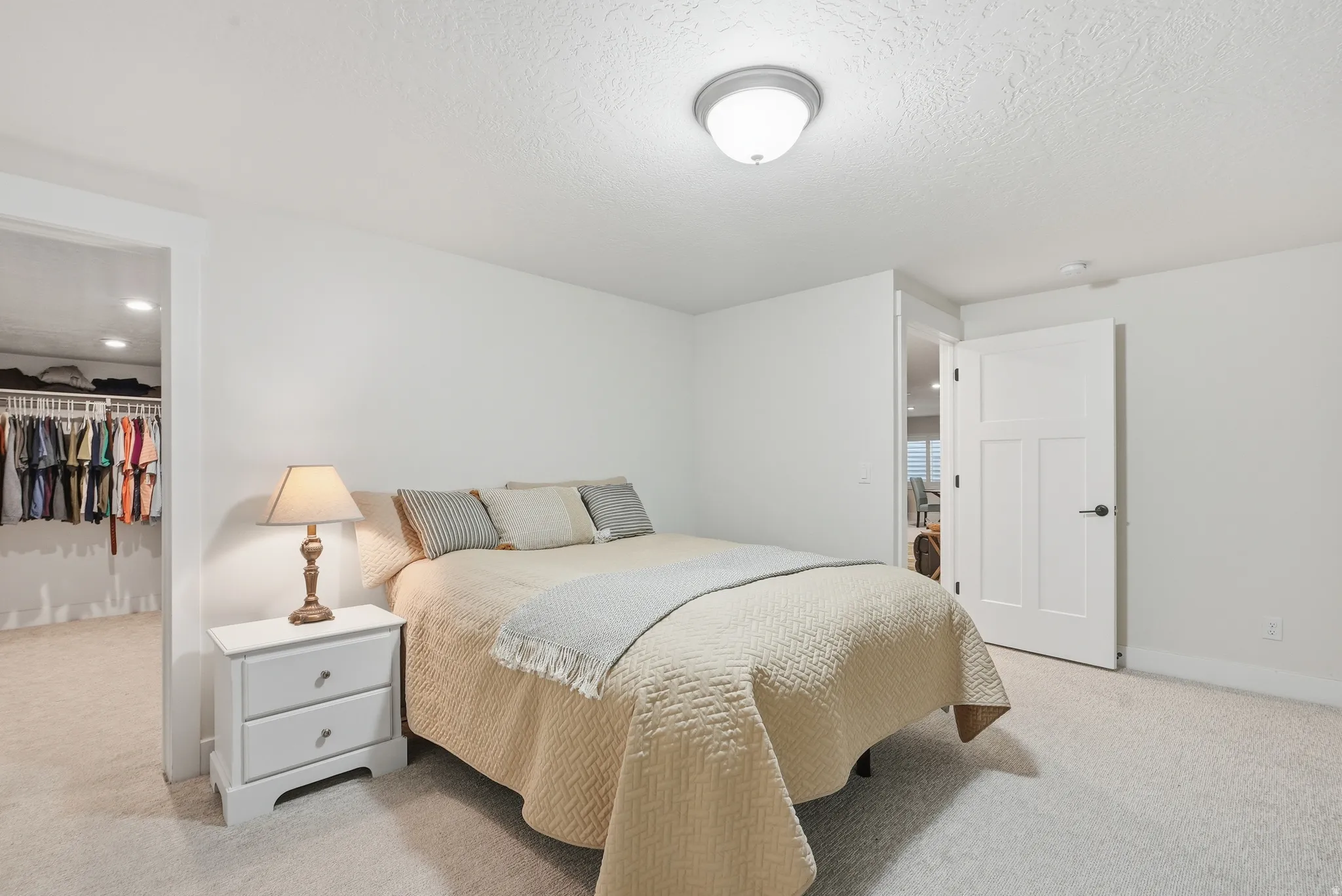 Bedroom featuring a spacious closet, light carpet, and a textured ceiling