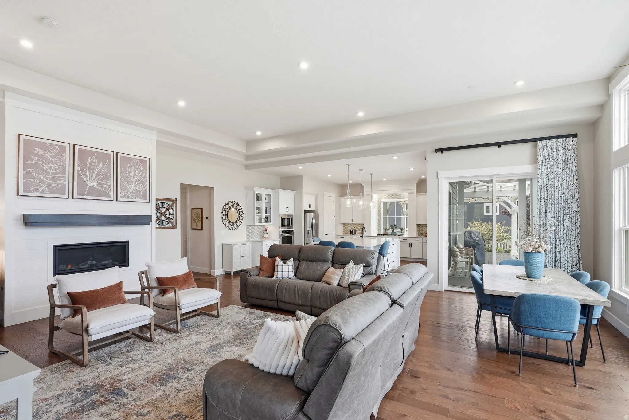 Living room featuring a glass covered fireplace, hardwood / wood-style floors, healthy amount of natural light, and suspended lighting