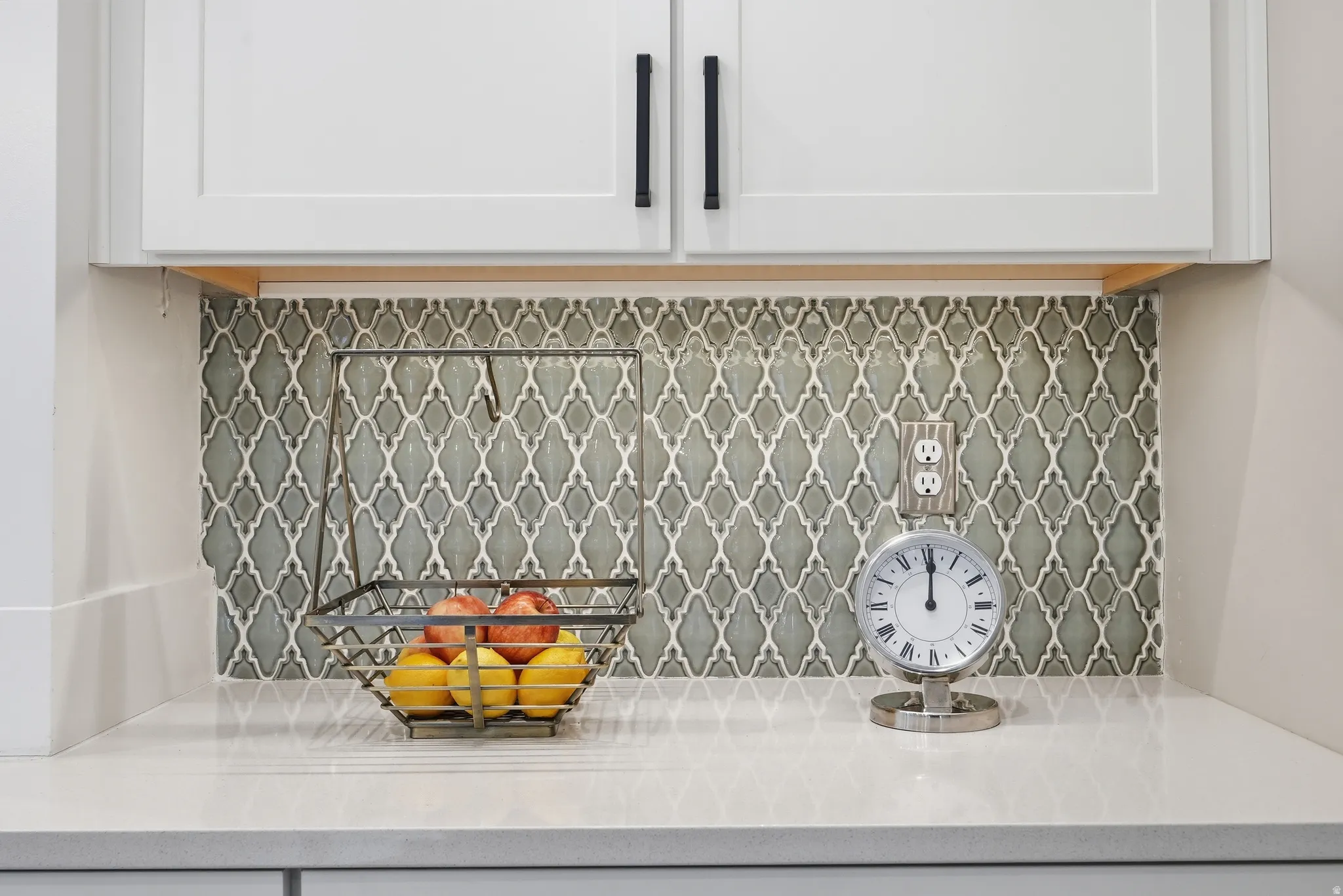 Kitchen view of light stone counters, backsplash, and white cabinetry