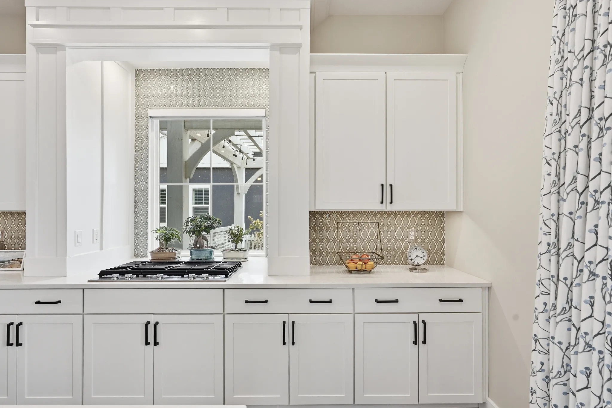 Bar area featuring white cabinetry, backsplash, stainless steel gas stovetop, and light stone counters