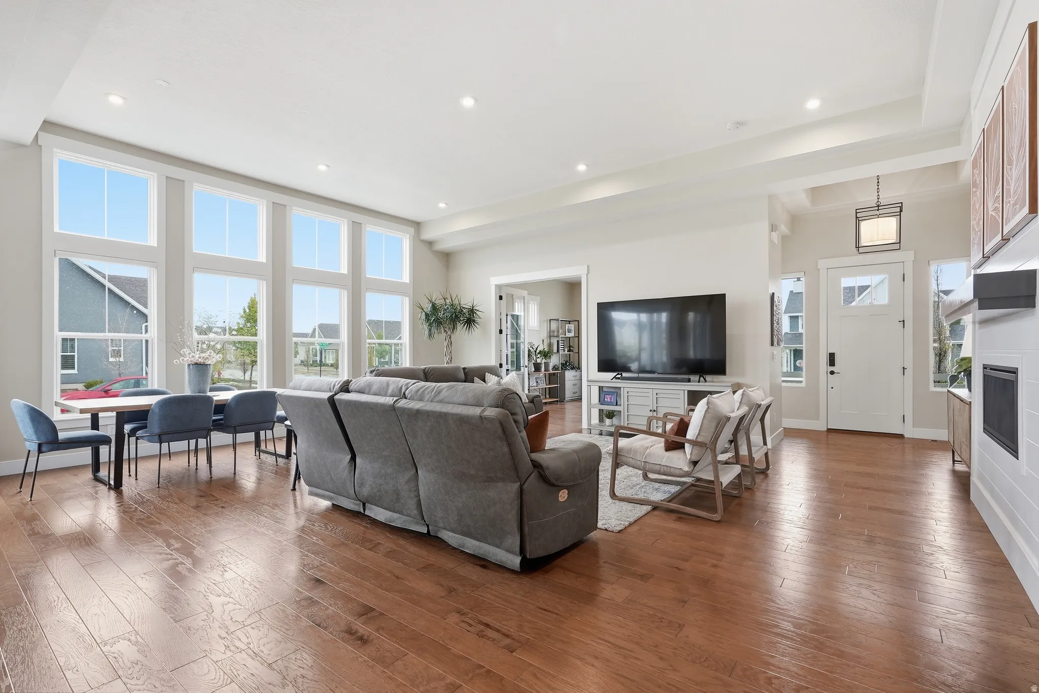Living area with a high ceiling, hardwood / wood-style floors, a glass covered fireplace, and recessed lighting