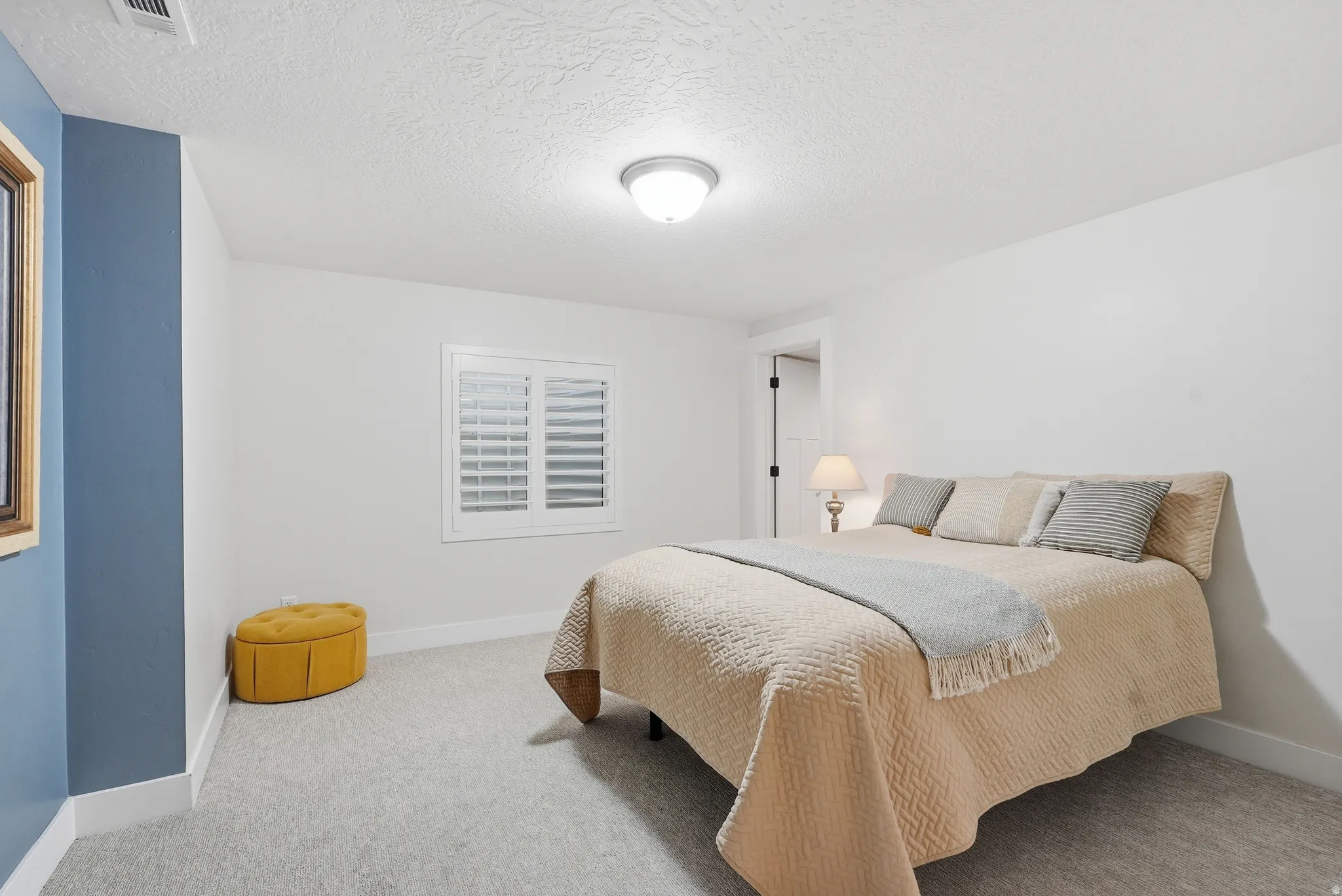 Bedroom with a textured ceiling and light carpet