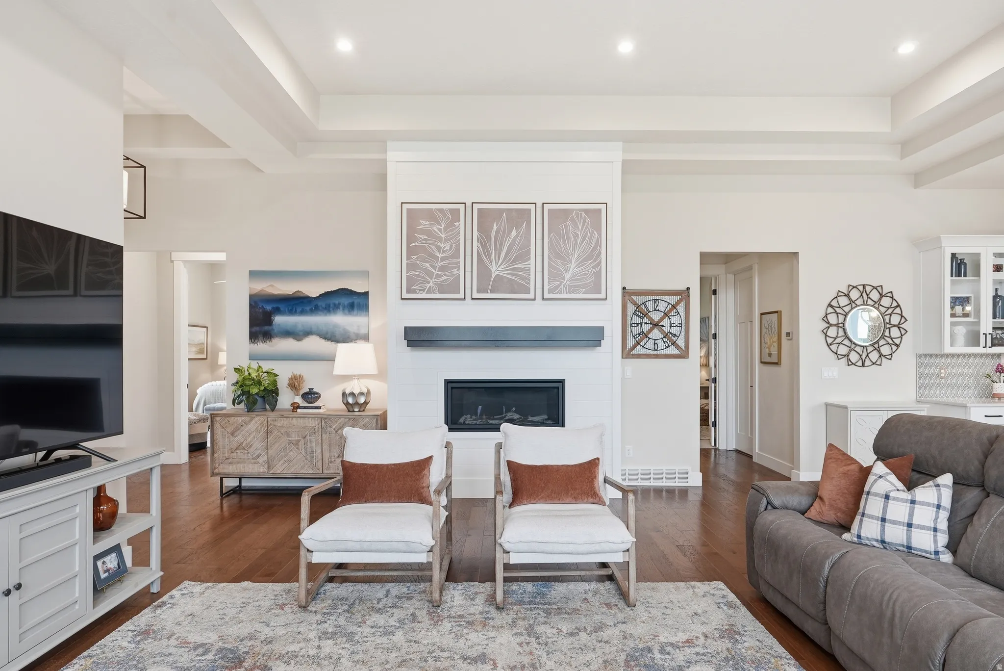 Living room featuring dark wood-style floors, a tray ceiling, recessed lighting, and a fireplace