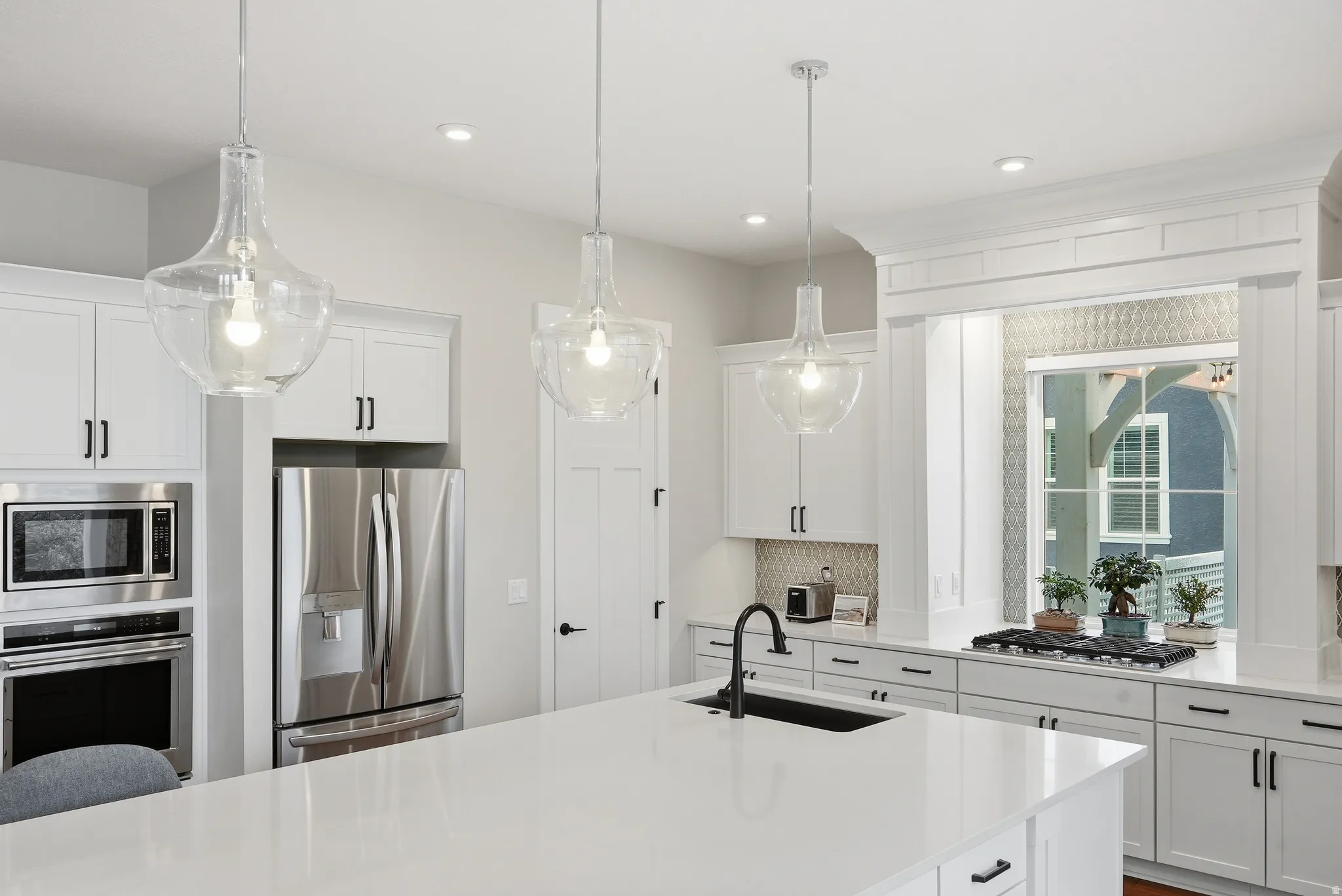 Kitchen with stainless steel appliances, white cabinets, light stone countertops, and tasteful backsplash