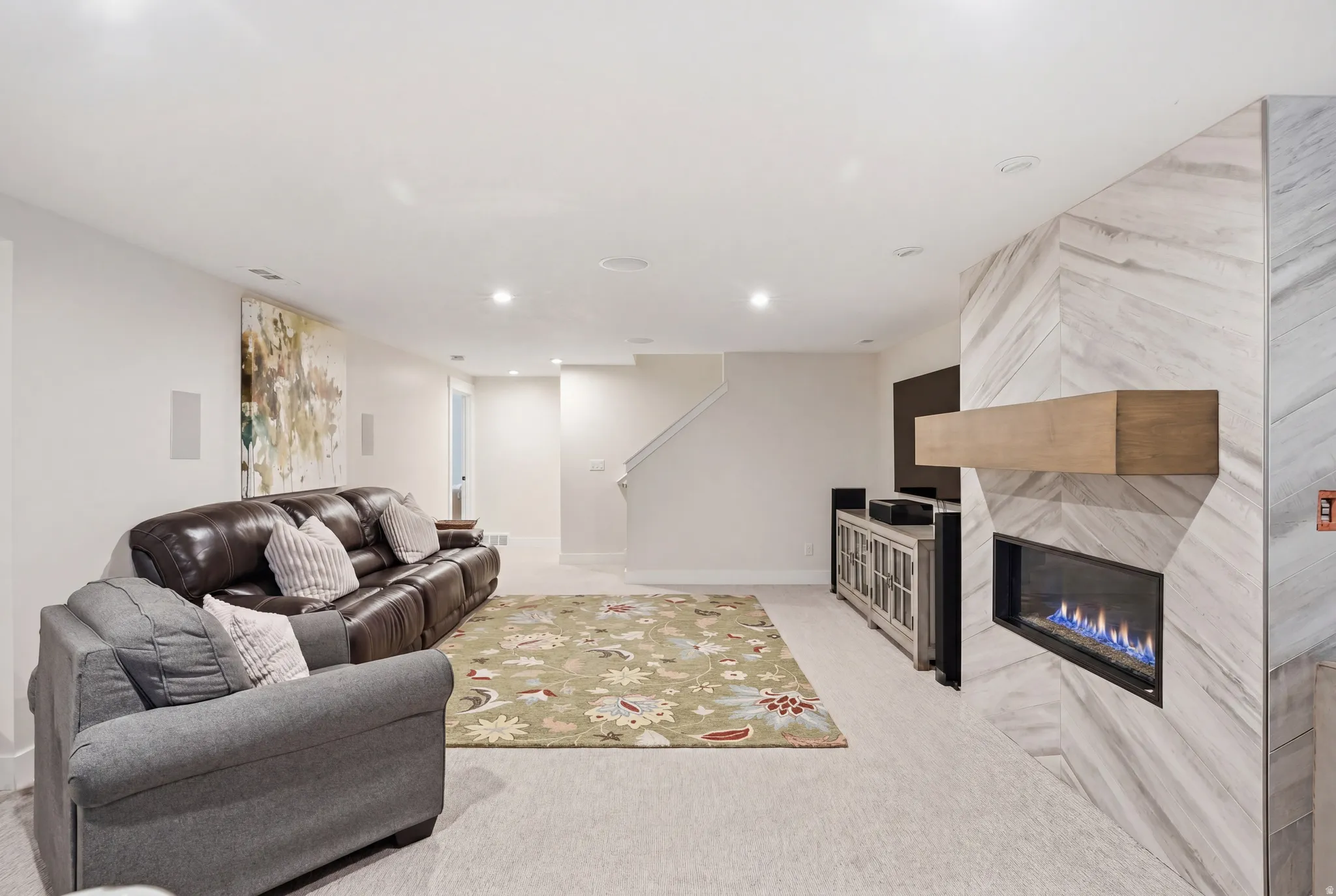 Living room with a fireplace, light carpet, and recessed lighting