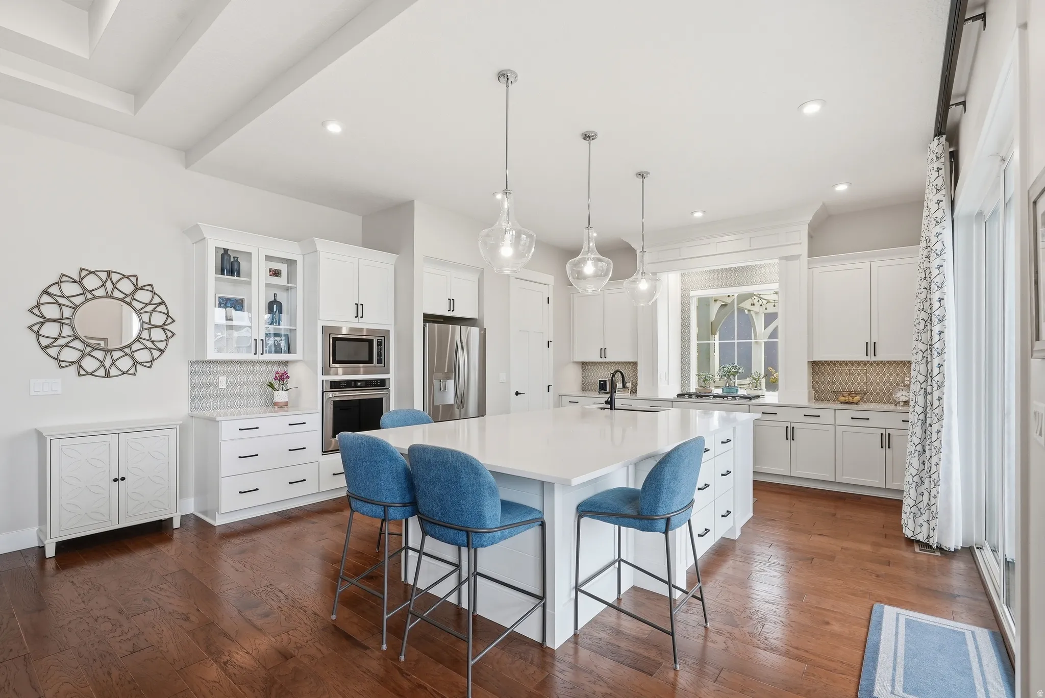 Kitchen featuring decorative backsplash, a breakfast bar area, an island with sink, and white cabinets