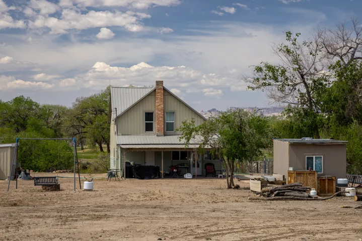 Rear view of house with a patio area, an outdoor structure, and a chimney