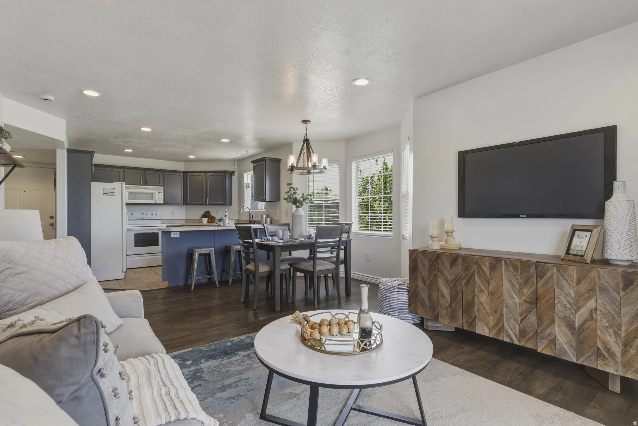 Living area with hanging lights and dark wood-style floors