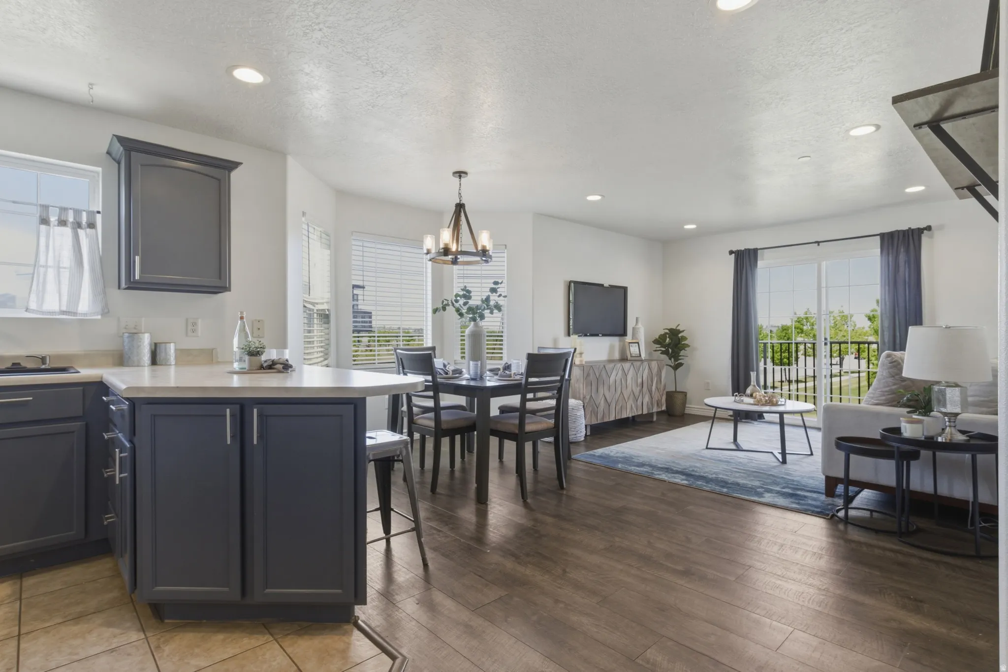 Kitchen featuring open floor plan, light countertops, a kitchen breakfast bar, a textured ceiling, and a peninsula
