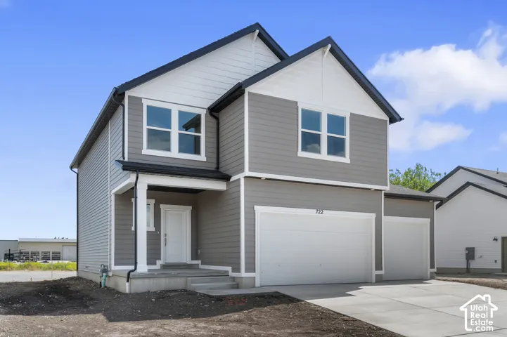 Contemporary exterior with gray siding and white trim, featuring a covered entry, multiple windows with white frames, and an integrated two-car garage