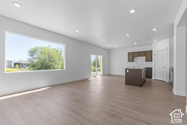 Open concept living area featuring wood-finish flooring, recessed lighting, a large horizontal window, and a sliding glass door