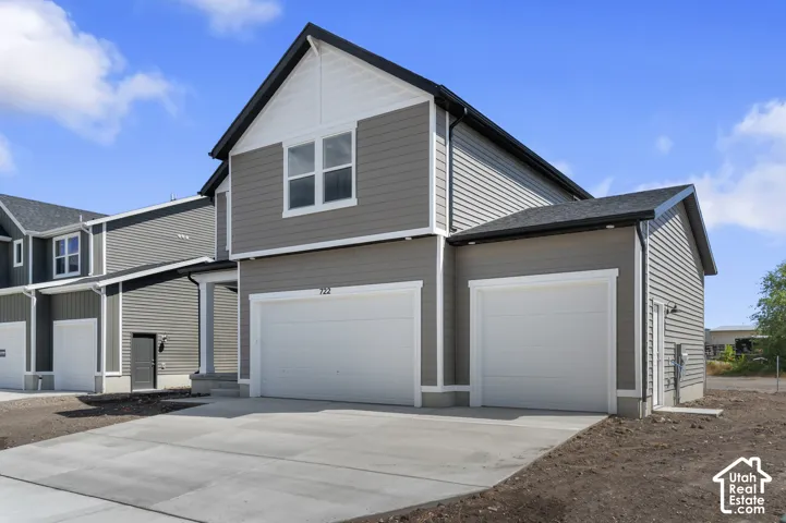 Exterior featuring gray horizontal siding with white trim, a black shingle roof, attached garage, and concrete driveway