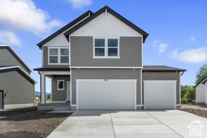 Two-story residence featuring gray siding, white trim accents, a covered entry porch, a two-car garage, and an additional single-car garage
