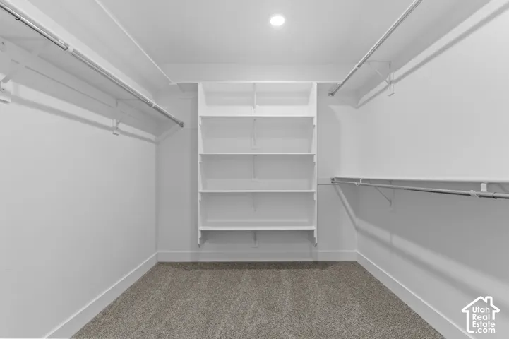 Spacious closet with built-in shelving, multiple clothing rods, and recessed lighting